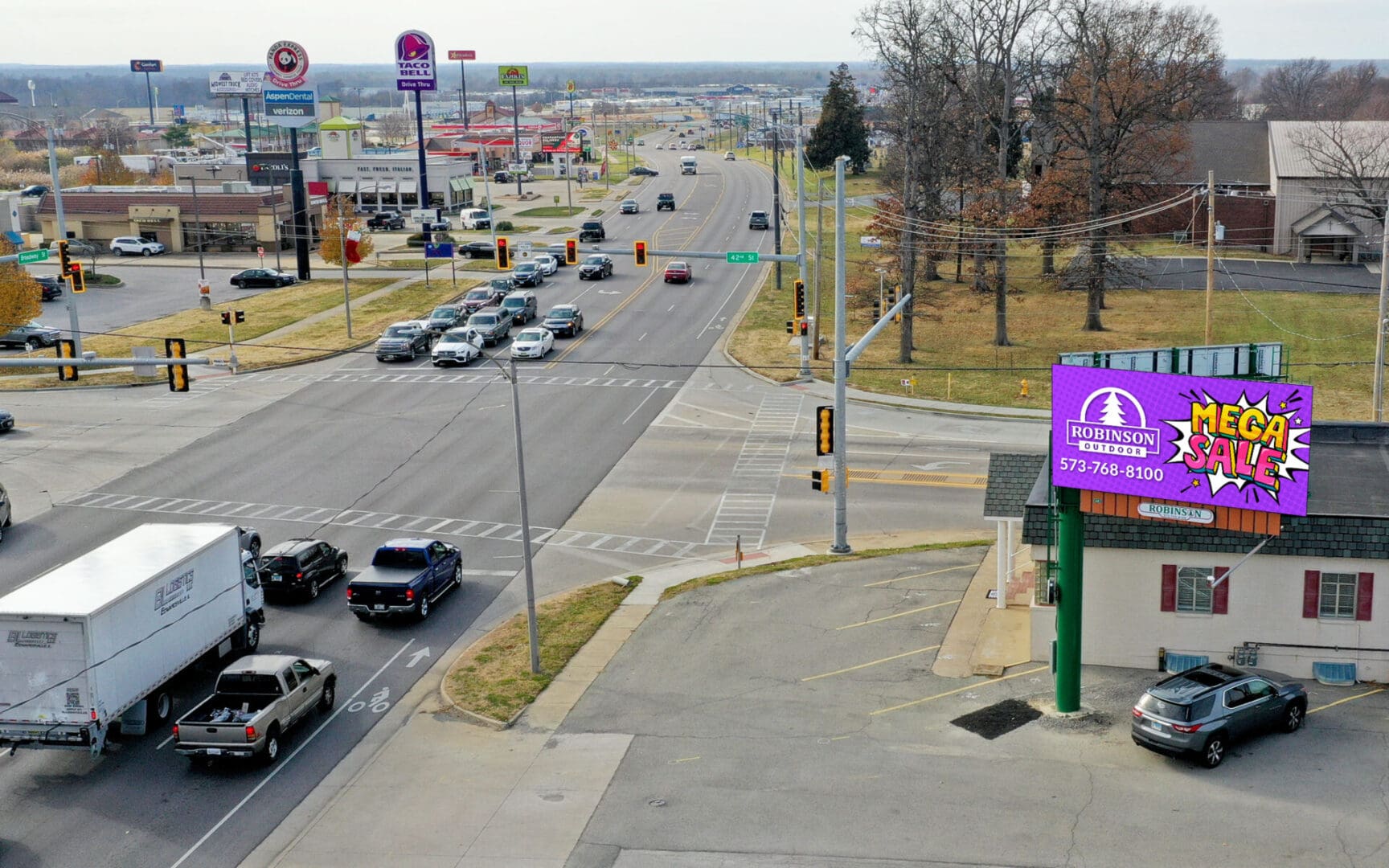 A view of an intersection with cars driving down the road.