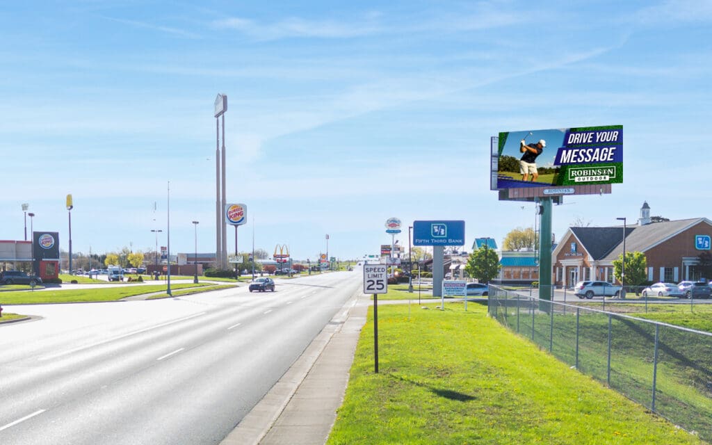 A sunny highway with billboards and green grass alongside.