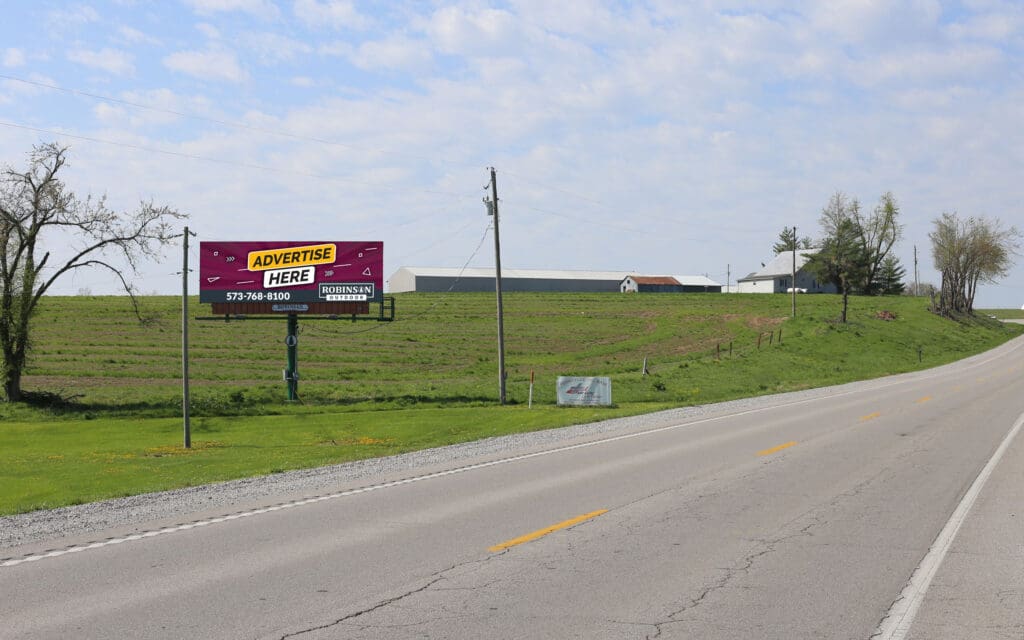 Billboard advertising a restaurant on a roadside with grassy fields.